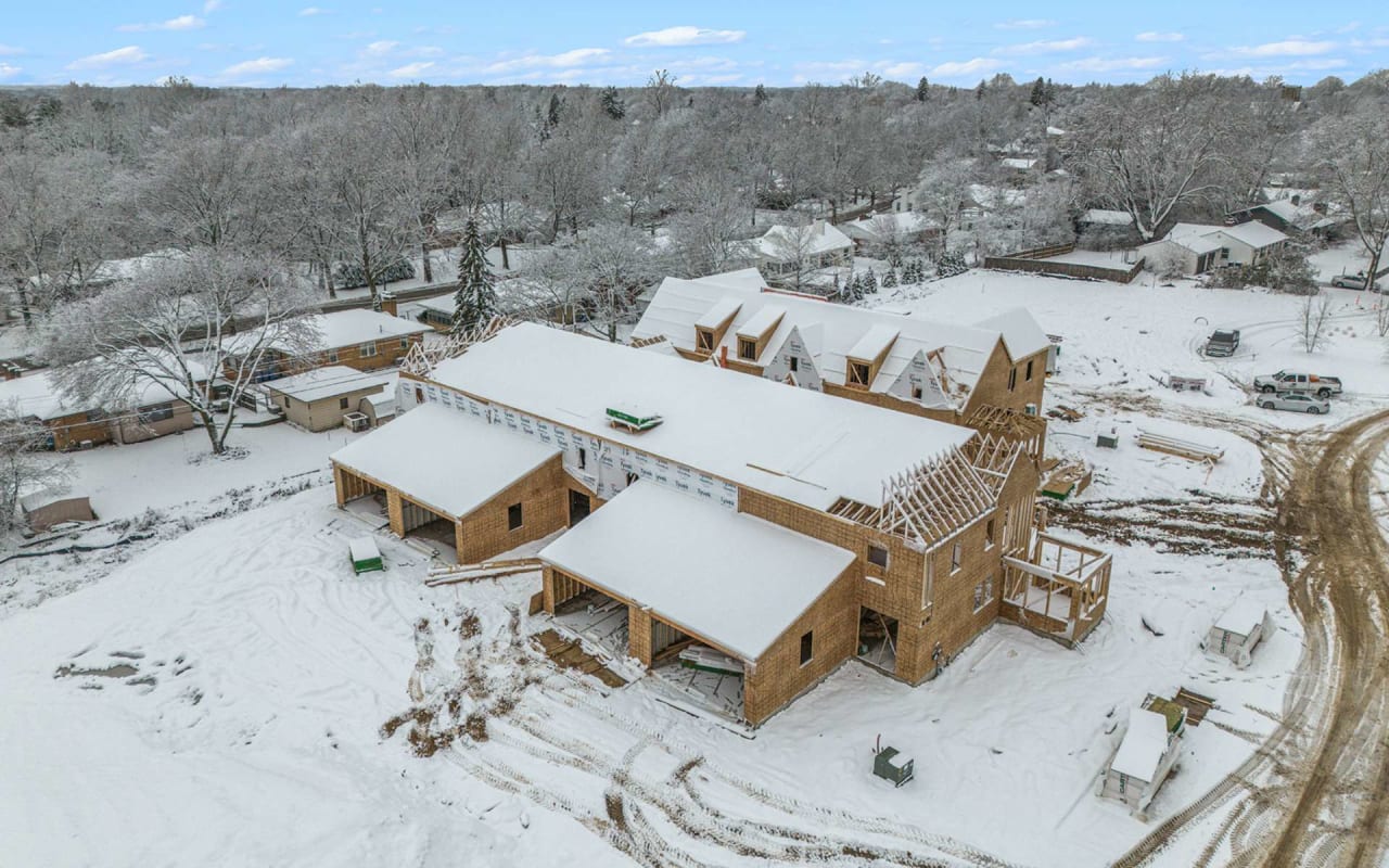 an aerial view of a under construction house framed out of wood in a snowy area