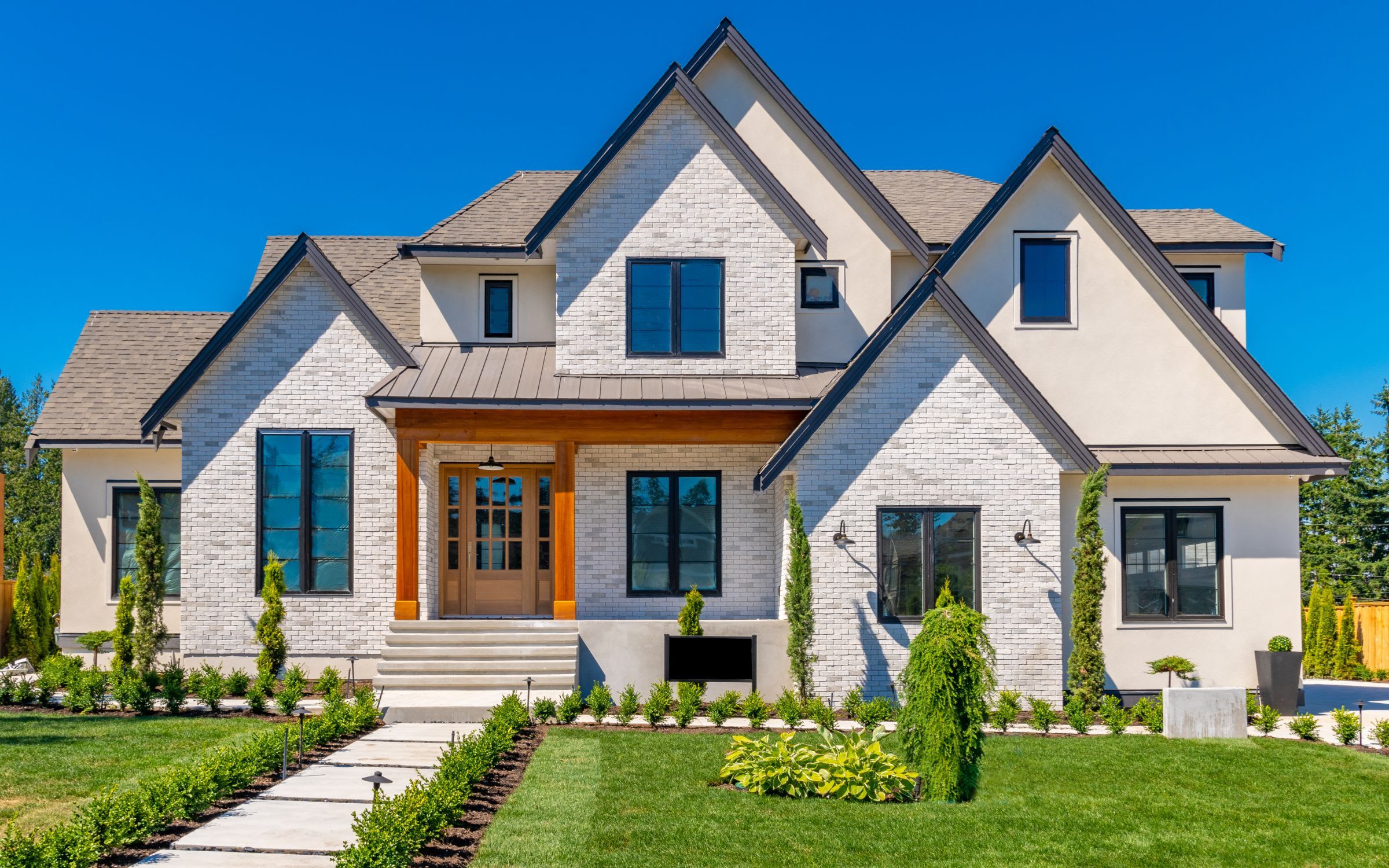 A spacious colonial house with a manicured lawn and mature trees.