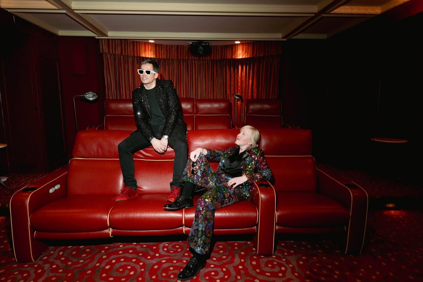 Brandon and Mallory Bogard in sequined suits among red leather theater seats