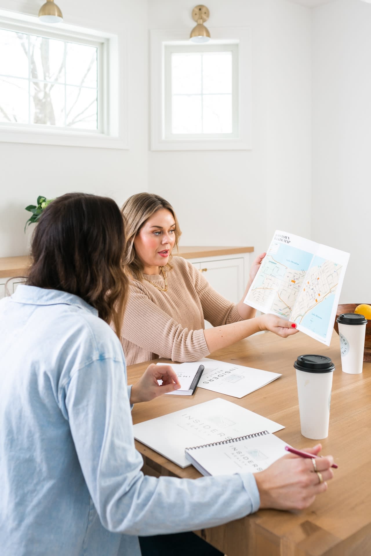 A group of professionals on a table, with a map and a notebook, actively discussing their plans.