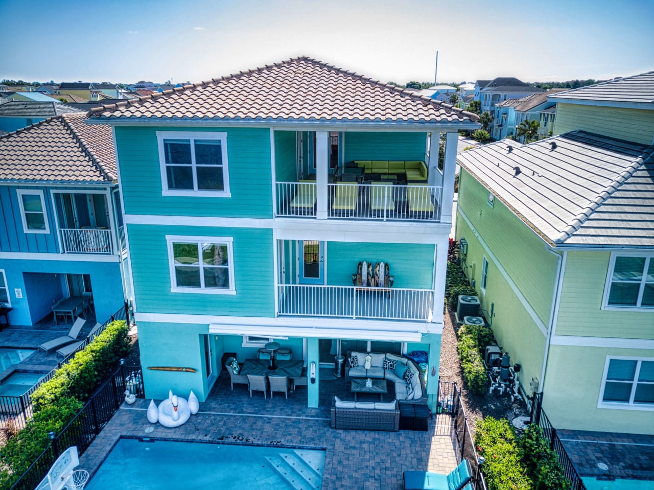 An aerial view of a blue house with a rectangular blue swimming pool and a balcony.