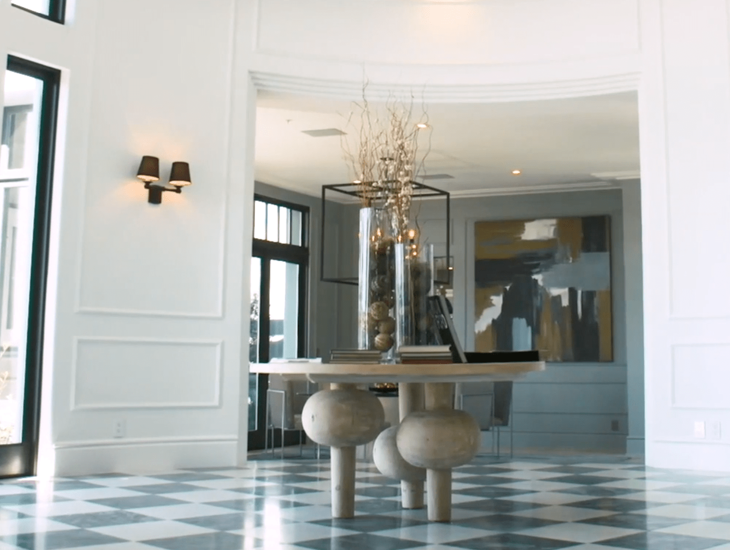 A table in a room with a checkered floor and a vase of flowers on the table