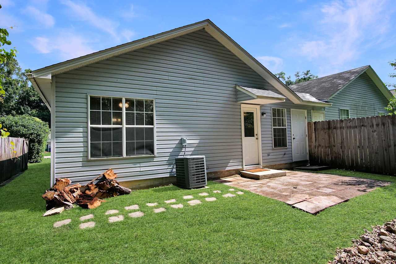 Photo of the rear of the home featuring lightly colored vinyl siding, a pavered patio, hardscaping, and a walking path of stone tiles  at 2709 Oak Park Court, Tallahassee, Florida 32308