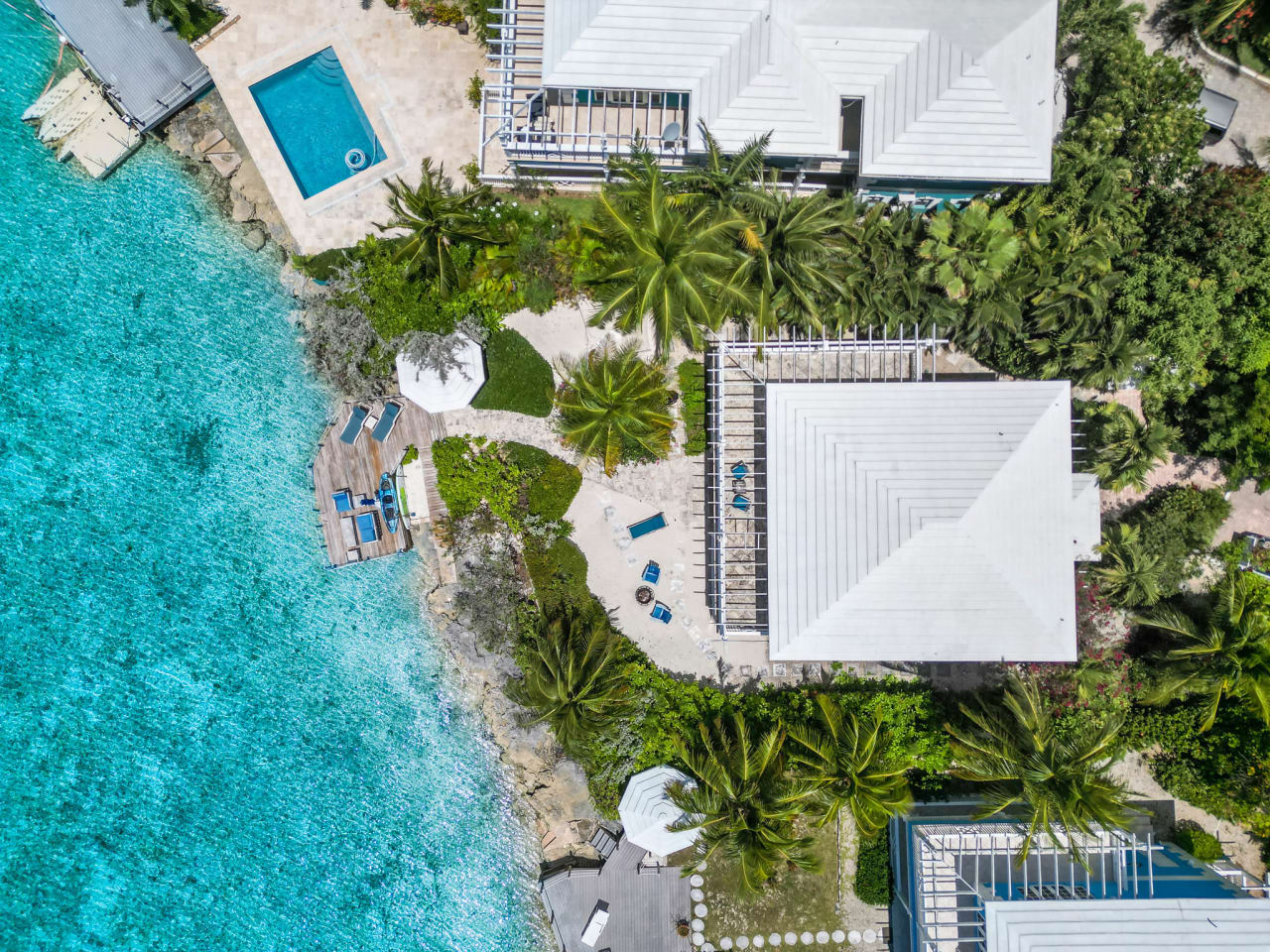 An aerial view of a tropical beach house with a swimming pool and a wooden deck.