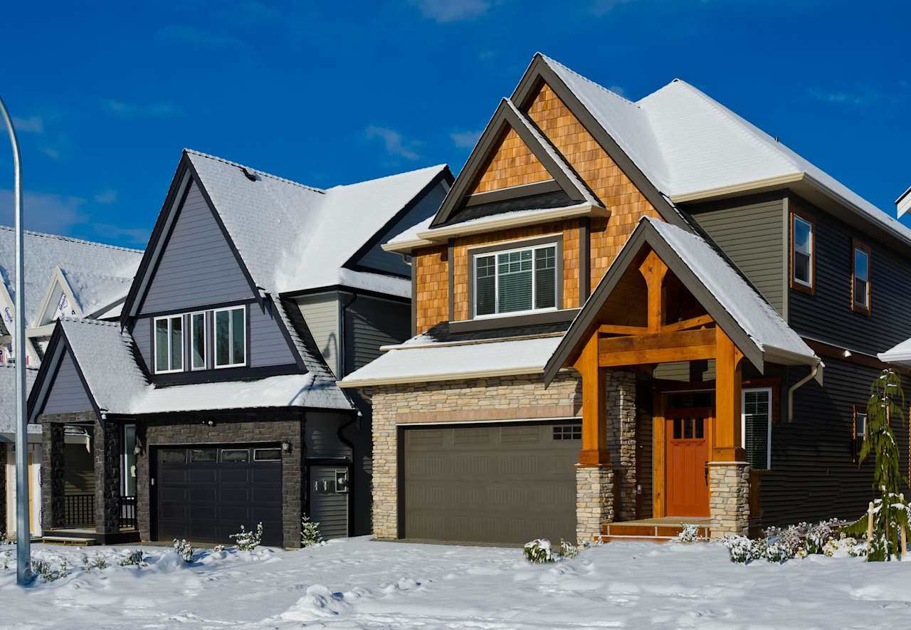 A row of houses with snow-covered roofs and a clear blue sky