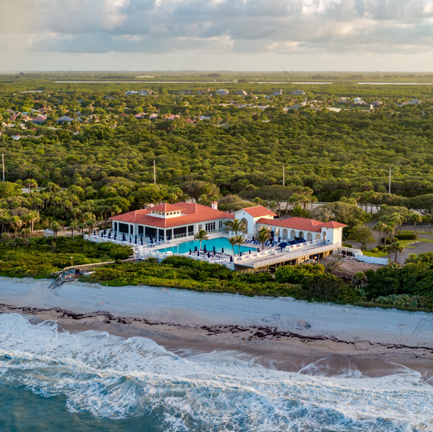 Oceanfront private beach club with red tile roof, swimming pool and cabanas on the Atlantic shoreline in Vero Beach, Florida, at golden hour