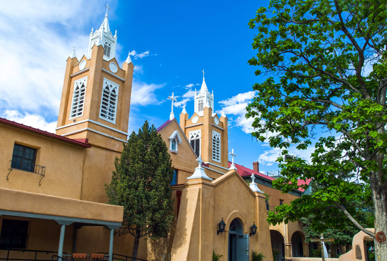 The San Felipe de Neri Church with two bell towers and a large tree in front of it.