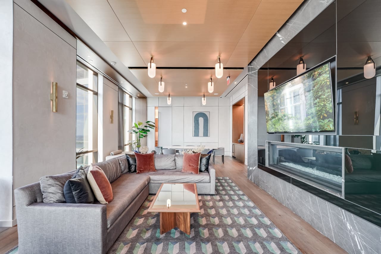 Contemporary living room with a large sectional sofa, modern decor, and a wall-mounted TV above a fireplace.