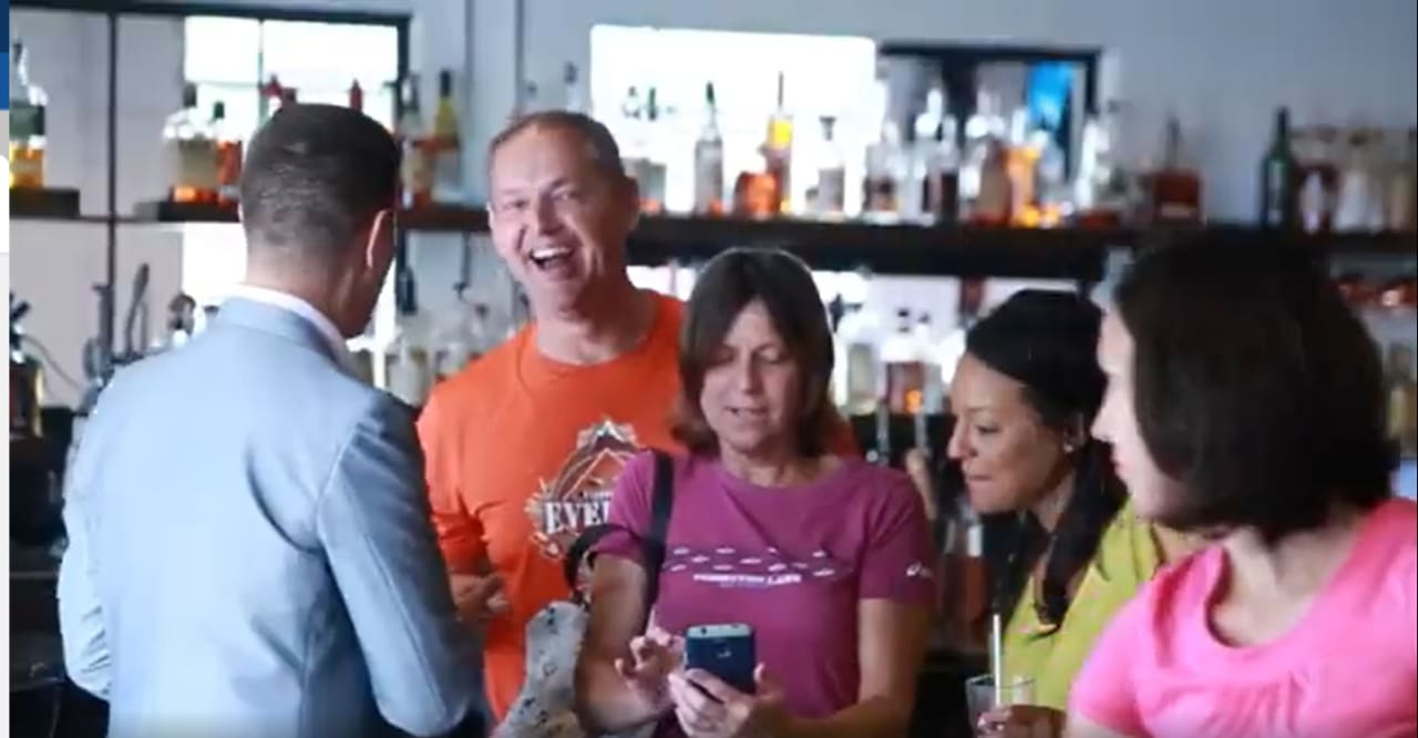 A group of people enjoying a social gathering, possibly in a bar or restaurant. The scene is lively and depicts people having a good time together.