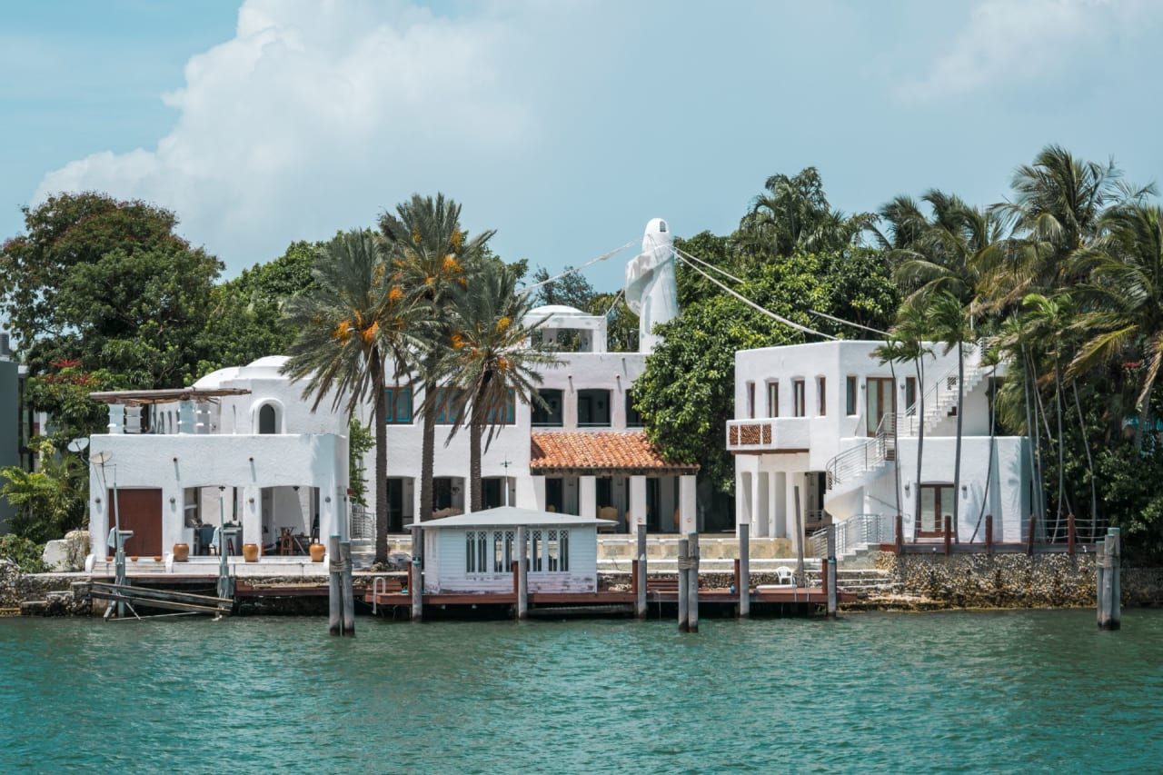 A white mansion with a distinctive spiral chimney sits on a waterfront property.