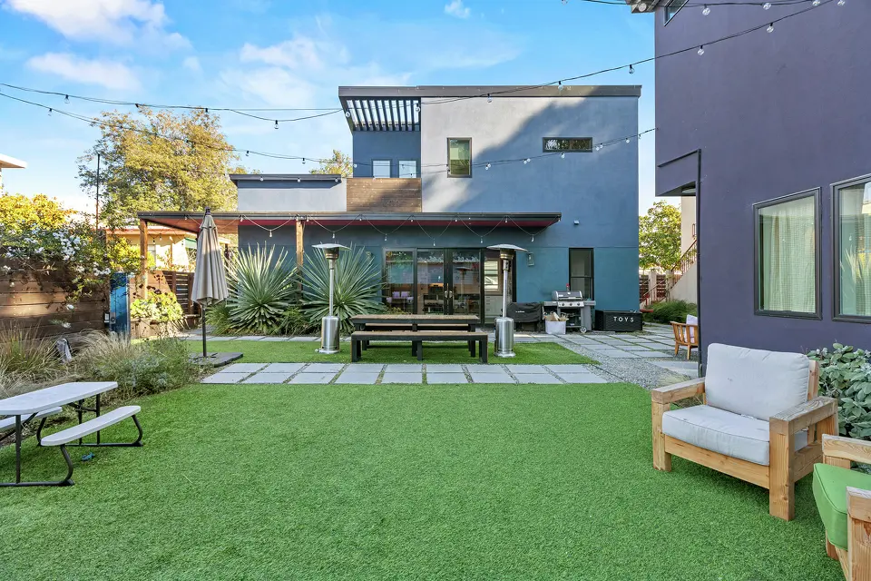 Modern co-living courtyard with artificial turf, outdoor seating, and string lights.