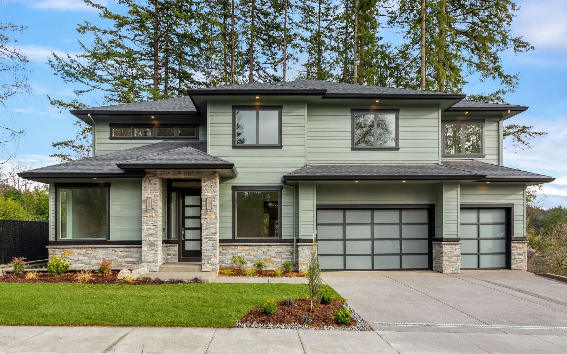 A large house with a lot of windows, a garage door, and a stone accent wall