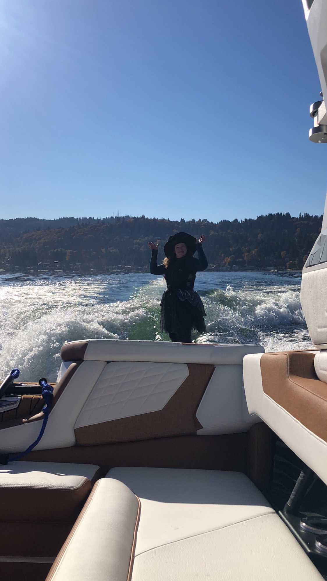 a lady wearing witch costume riding a waveboard next to the yatch