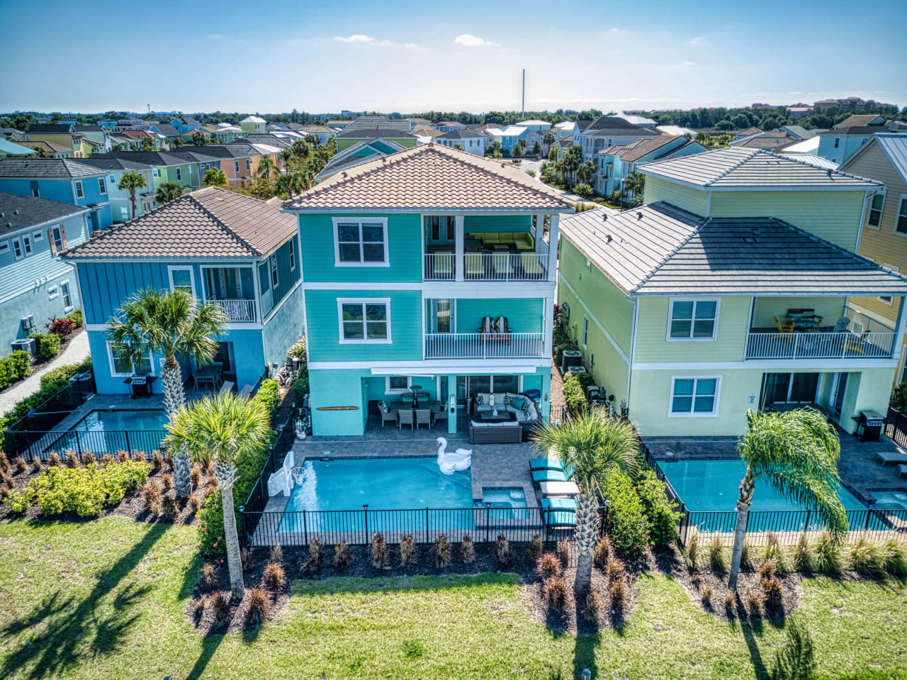 An aerial view of a single-family home with a rectangular, blue swimming pool in the backyard.