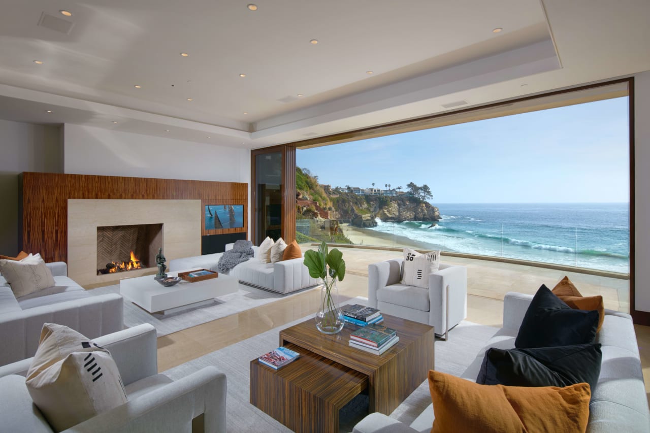 Spacious living room in a luxury beachfront property with a large window providing a scenic ocean view.