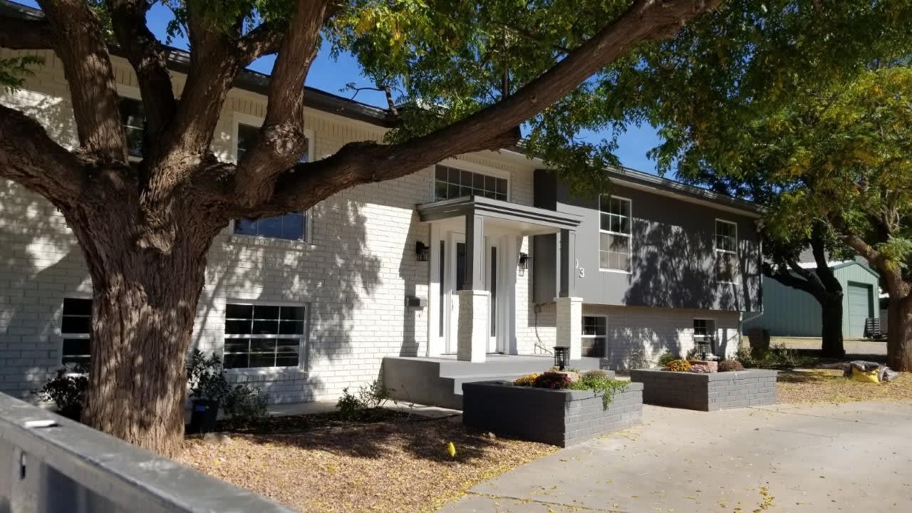 A large white brick house with a tree in front of it.