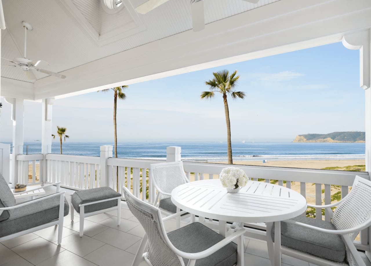 A balcony with a table and two chairs overlooking the ocean