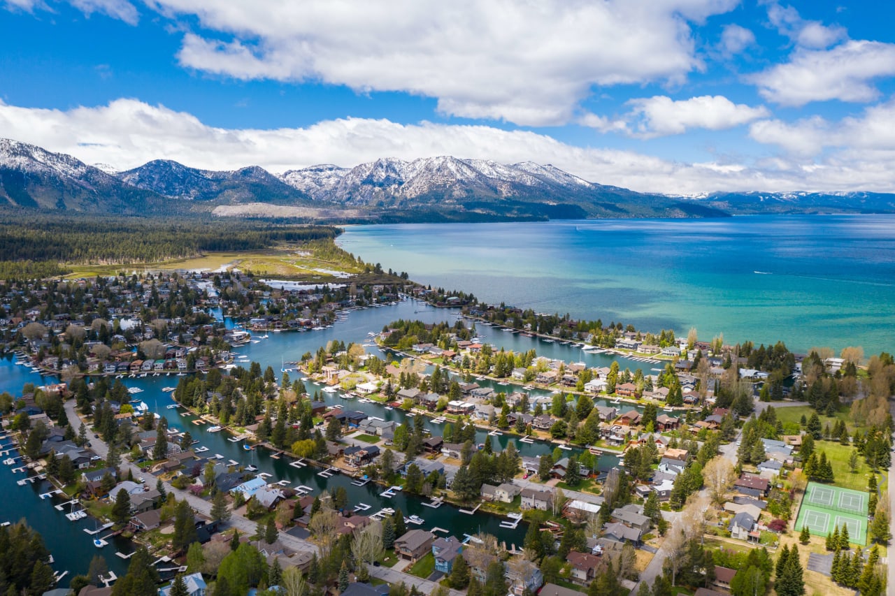 Aerial view of South Lake Tahoe, California, showcasing the vibrant waterfront community with homes, marinas, and mountains.