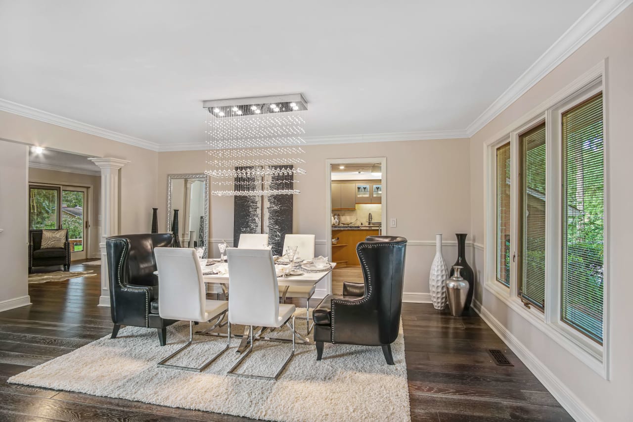 A well-decorated dining room with a contemporary and elegant style. The walls are painted in a soft beige or light tan color, complementing the dark hardwood floors.