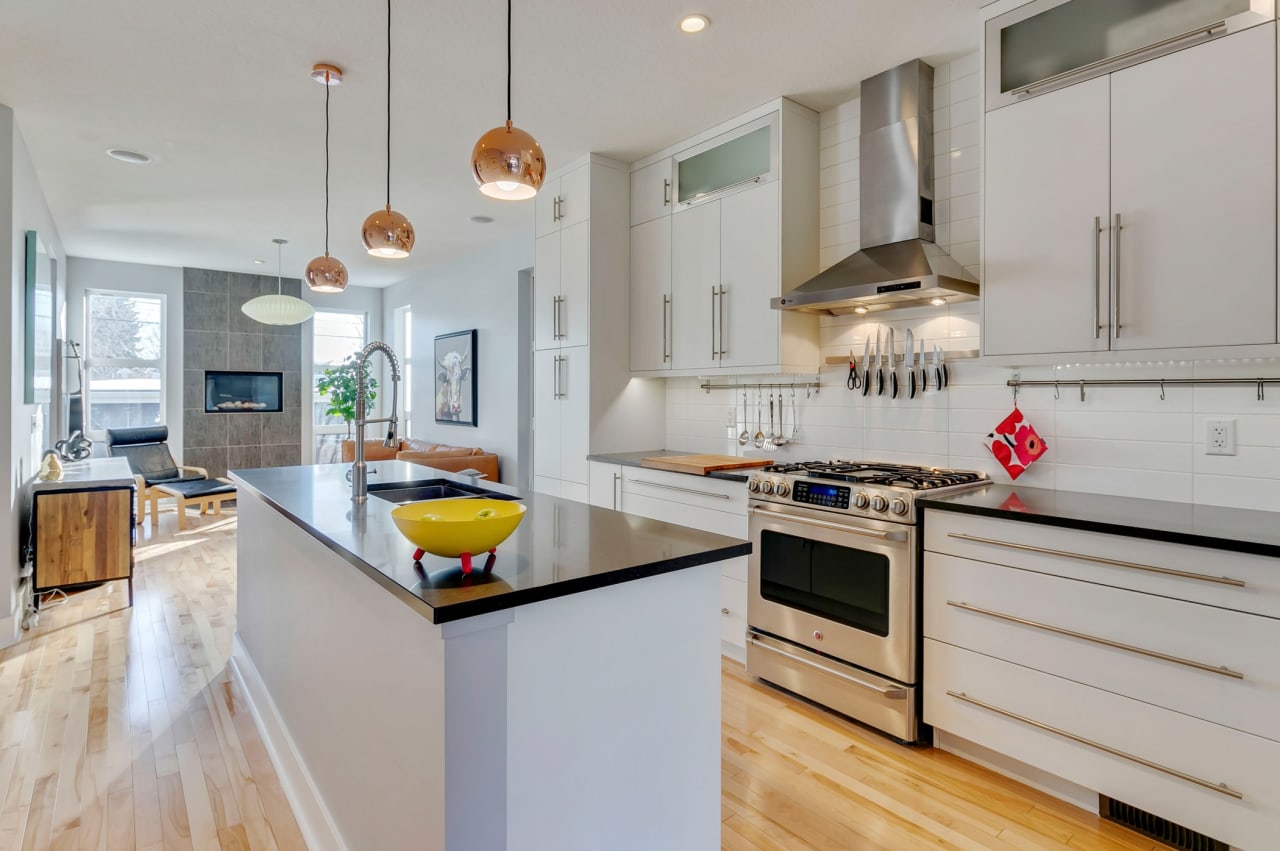 A kitchen with a stainless steel stove, a white sink, and a wooden bowl on the island