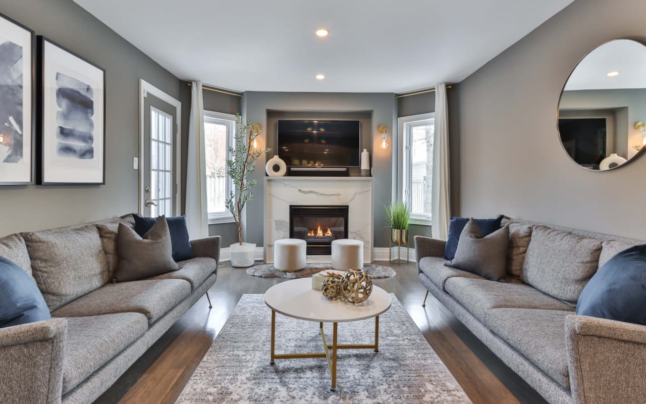 A cozy living room with two gray-colored couches facing a fireplace.