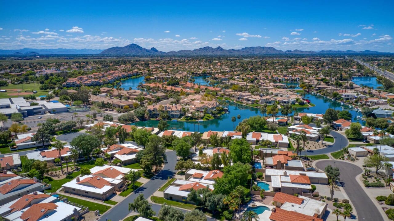 An aerial view of a residential neighborhood with a lake and mountains