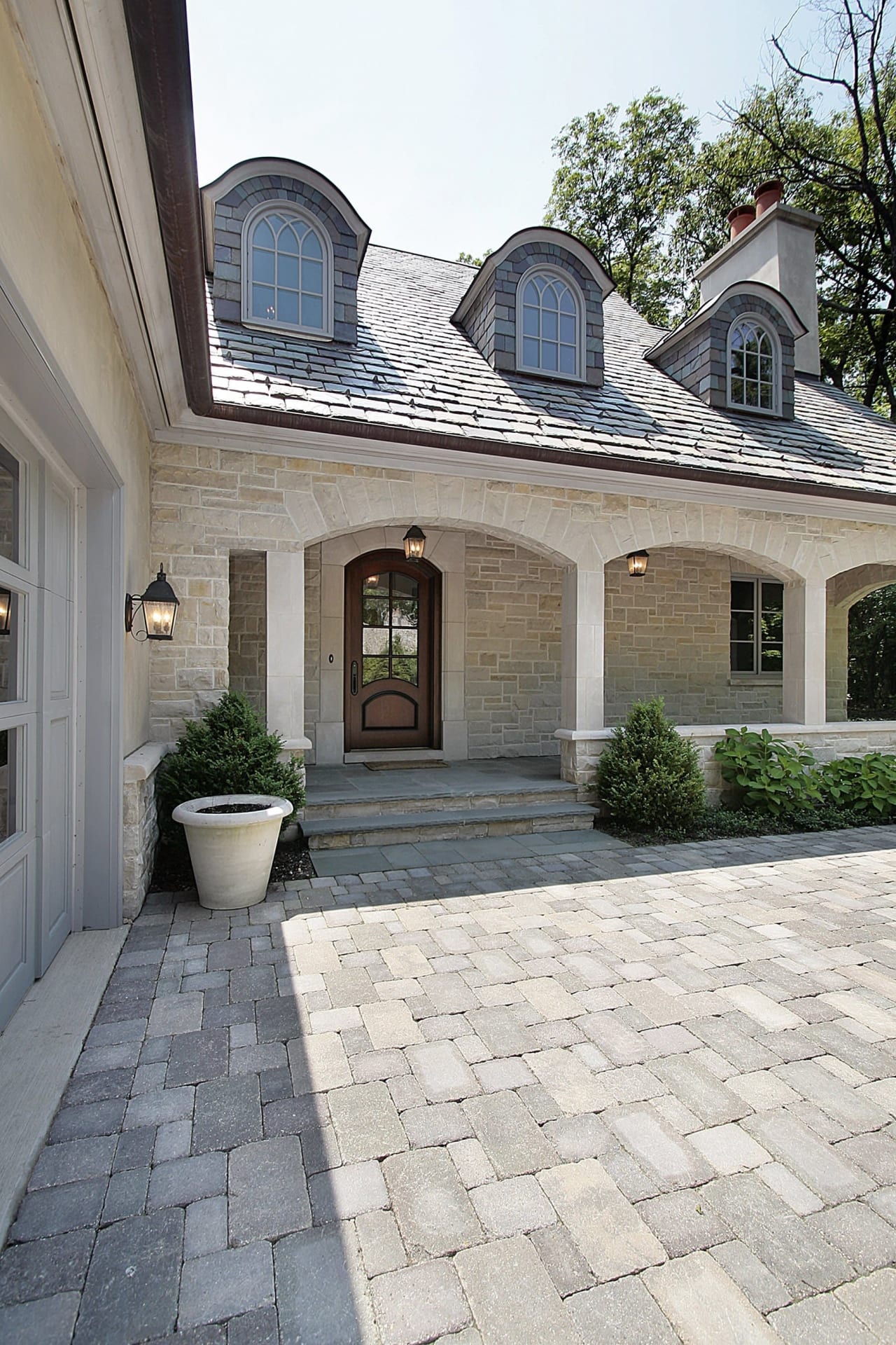 A luxury home with a stone exterior and a brick driveway.