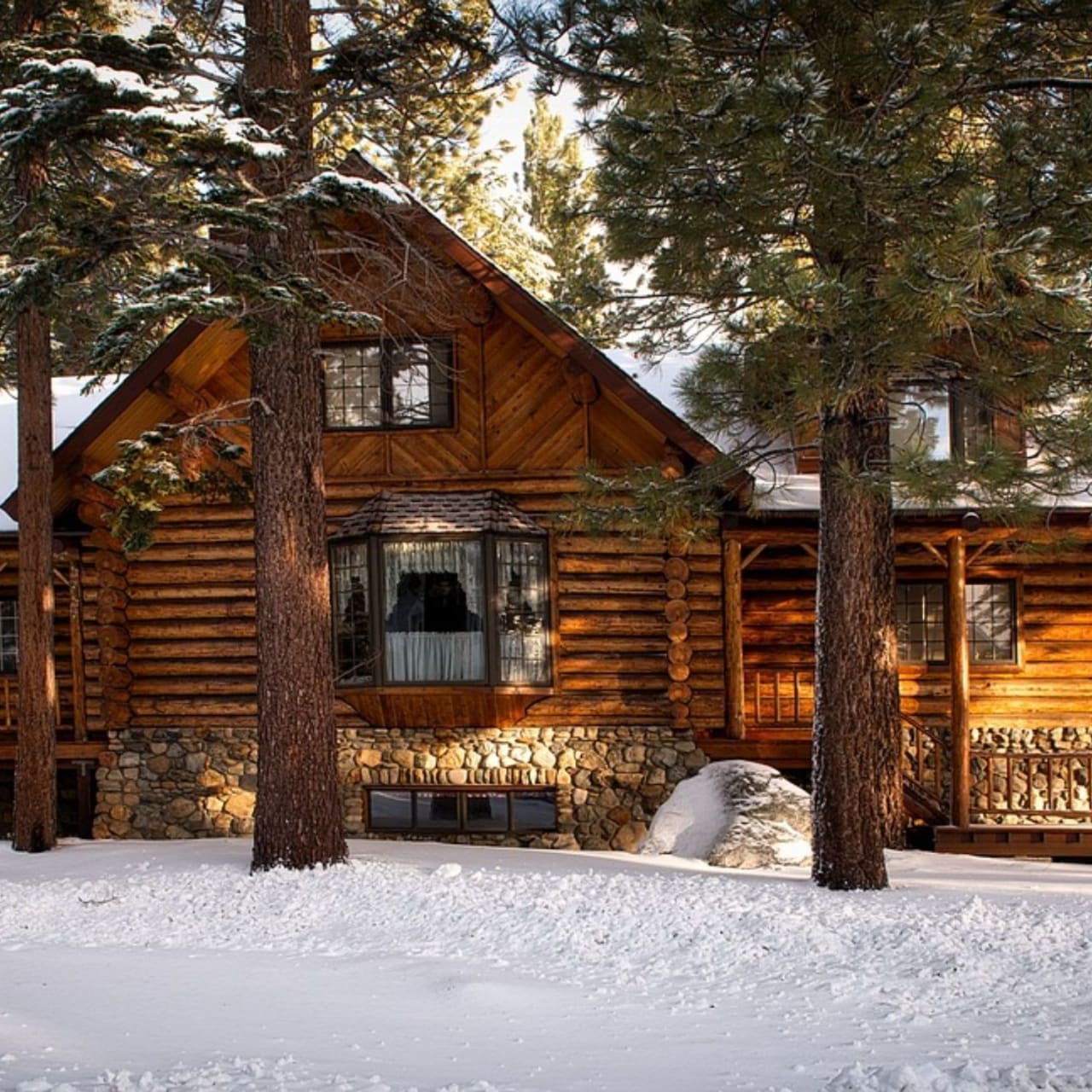 A log cabin nestled among snow-covered pine trees in winter.