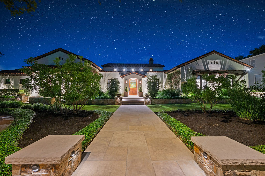 A house at night with a sidewalk leading up to the front door. 