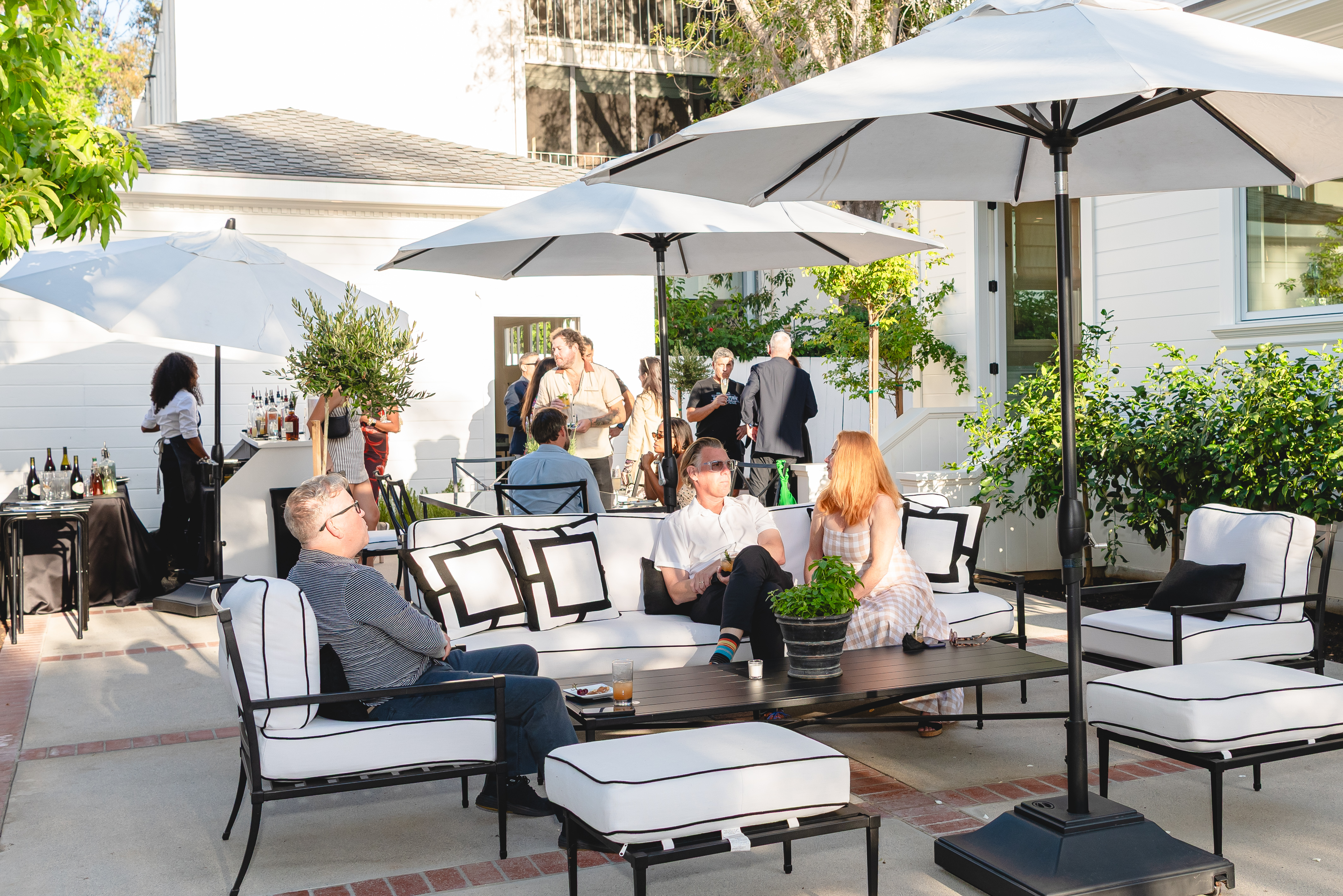 Courtyard with market umbrellas and white outdoor lounge seating filled with guests