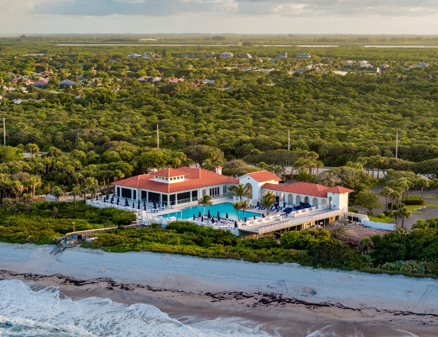 Aerial view of an oceanfront beach club and luxury barrier island neighborhood at sunset in Vero Beach, Florida