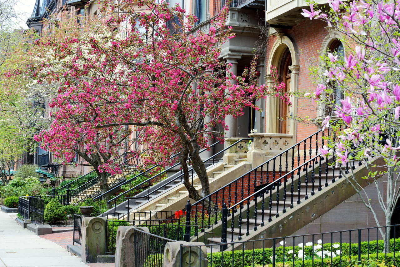 A row of historic brick townhouses with ornate staircases and wrought iron railings