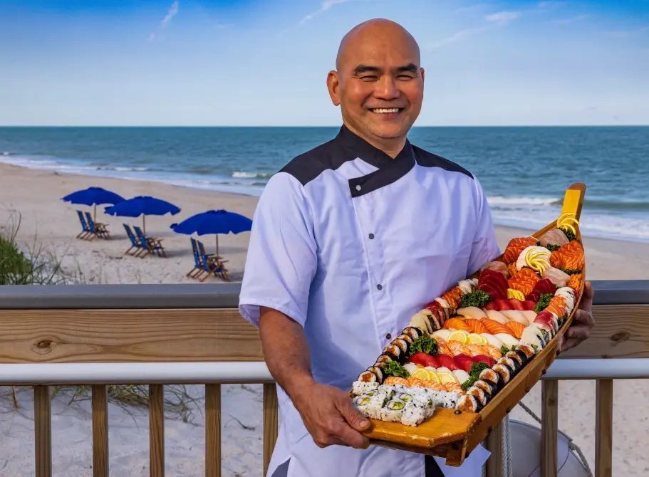 The pink oceanfront clubhouse and pool at Sea Oaks Beach and Tennis Club, brick terrace and lounge seating overlooking the Atlantic shoreline.