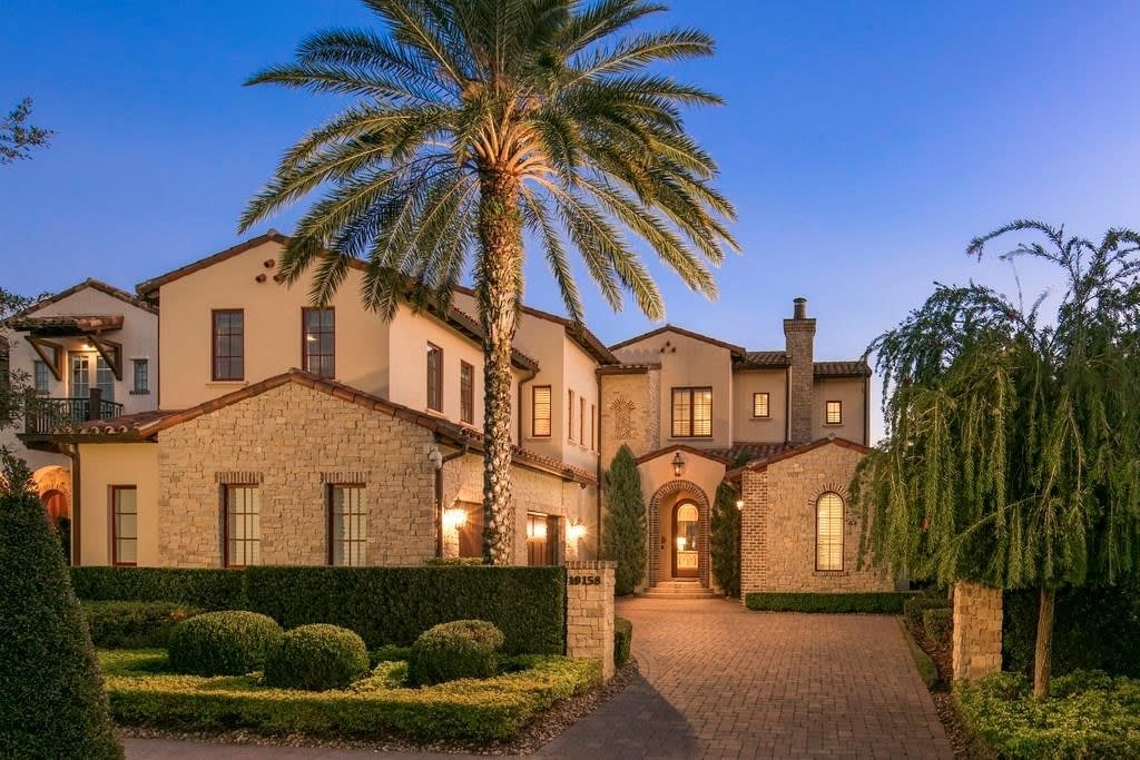 A large house with a driveway, a front lawn, and a palm tree in front of Golden Oak at Walt Disney World Resort, Florida.