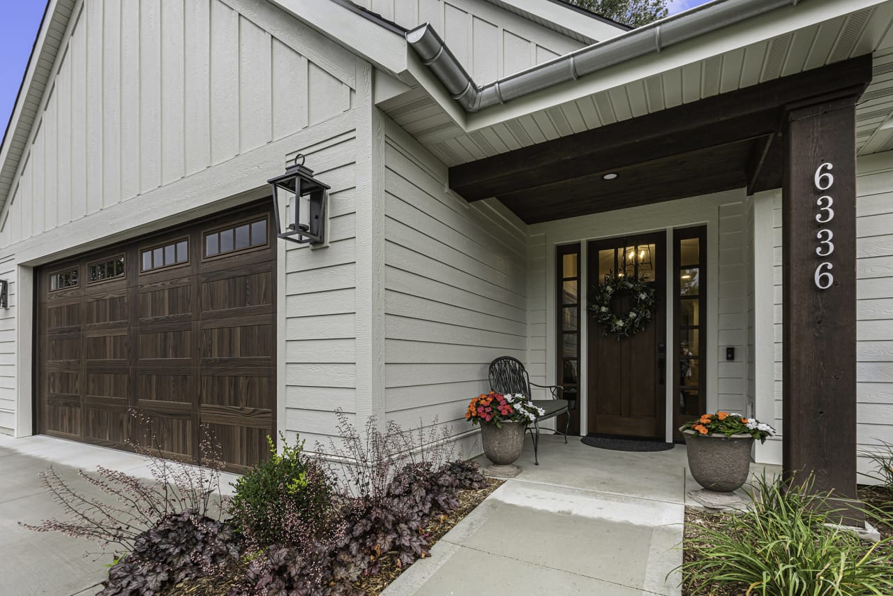 A front porch of a house with a wooden door and a wreath on the front door