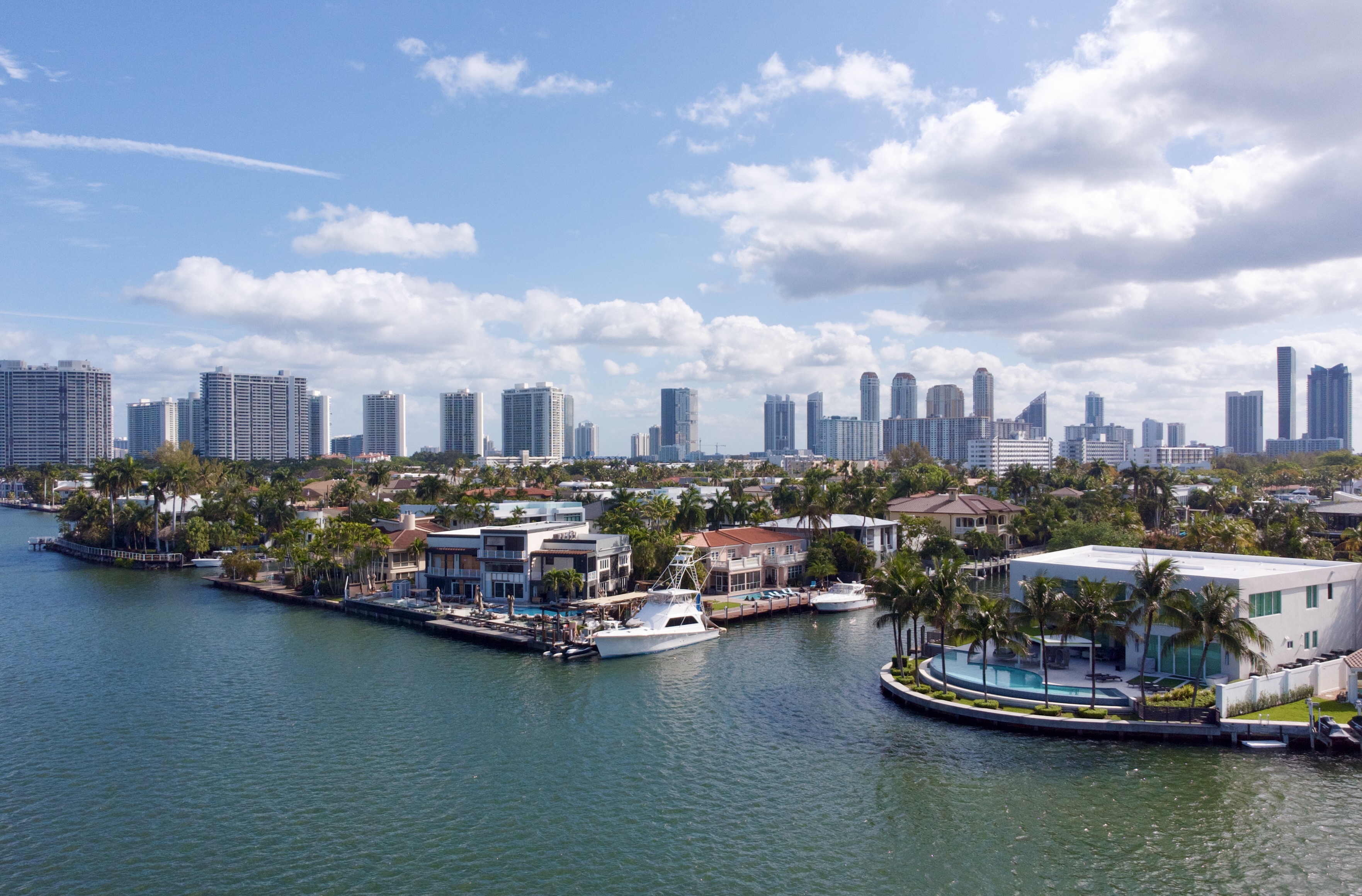 Aerial view of luxury waterfront estates on Maule Lake in Eastern Shores with the Williams Island and Sunny Isles Beach skylines in the background