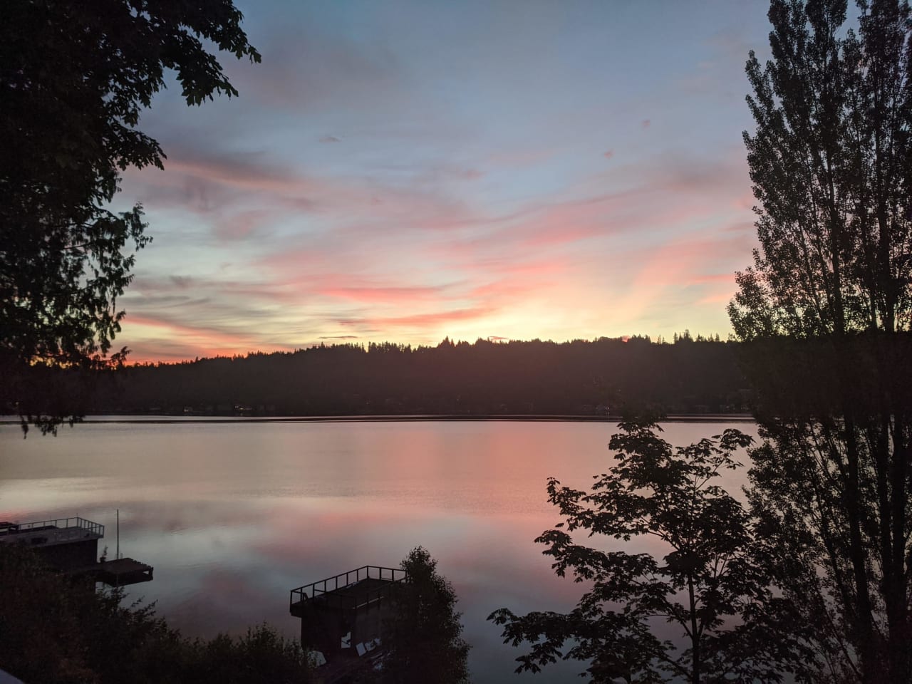 a sunset over a lake with a dock in the foreground