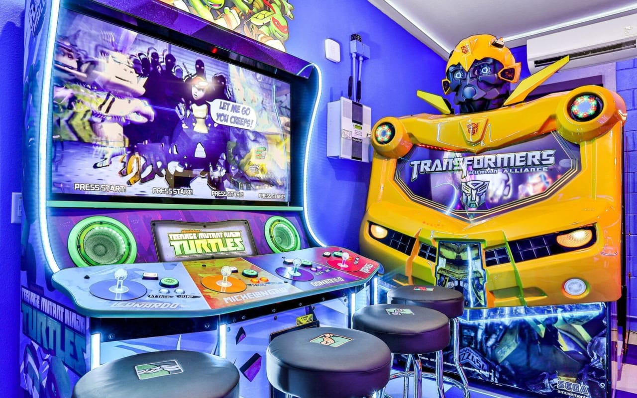 A game room with a Teenage Mutant Ninja Turtles arcade game and a Transformers arcade game.