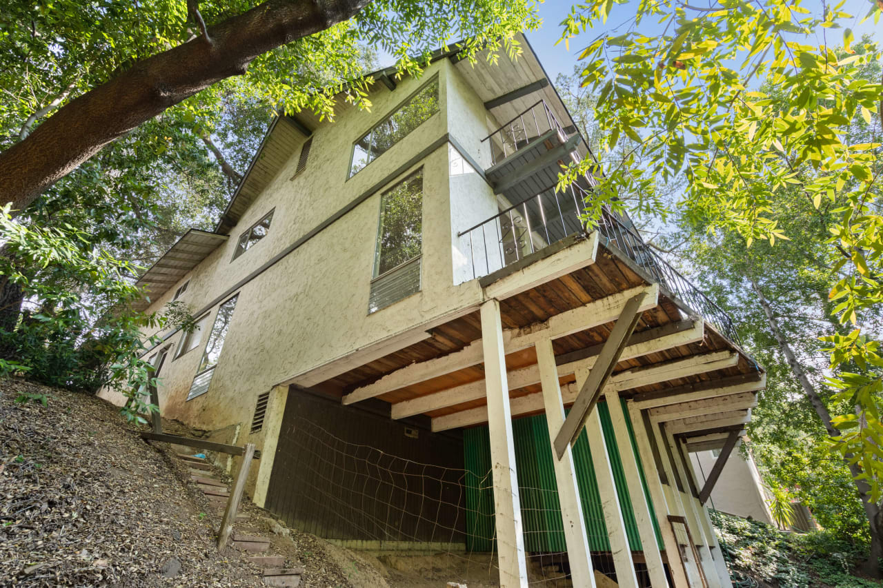 Side view of back of home showing 3 stories on hillside with trees