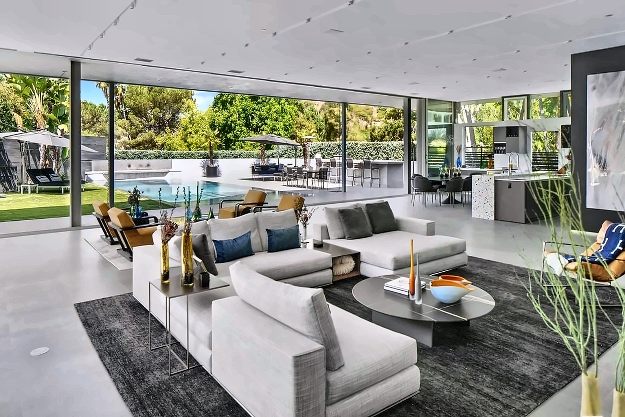 Open-plan Beverly Hills living room with floor-to-ceiling glass doors open to the pool and gardens