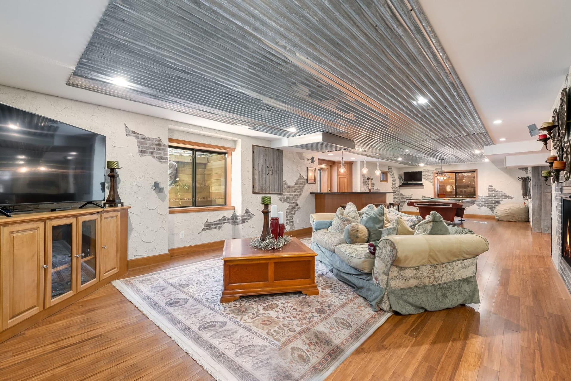 Living room with a couch, mounted TV, fireplace, and windows with an outdoor view