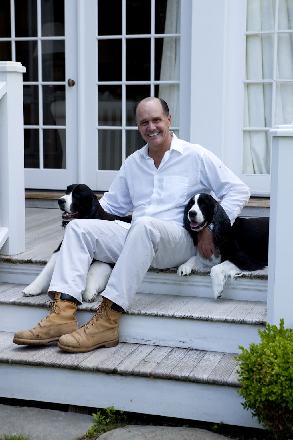 Jeffrey Collé sitting on the porch with two dogs