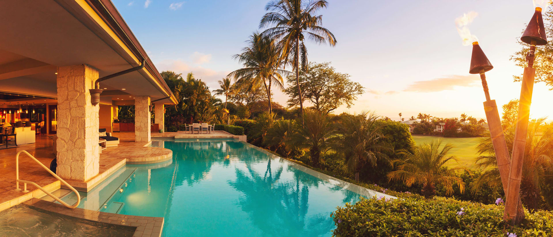 A tropical house with a large swimming pool and palm trees