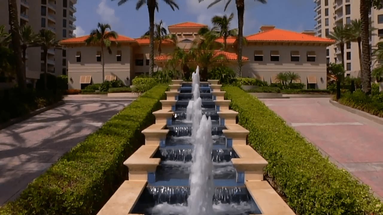 An entrance of luxury resort condos with small fountains in the middle isle of the road