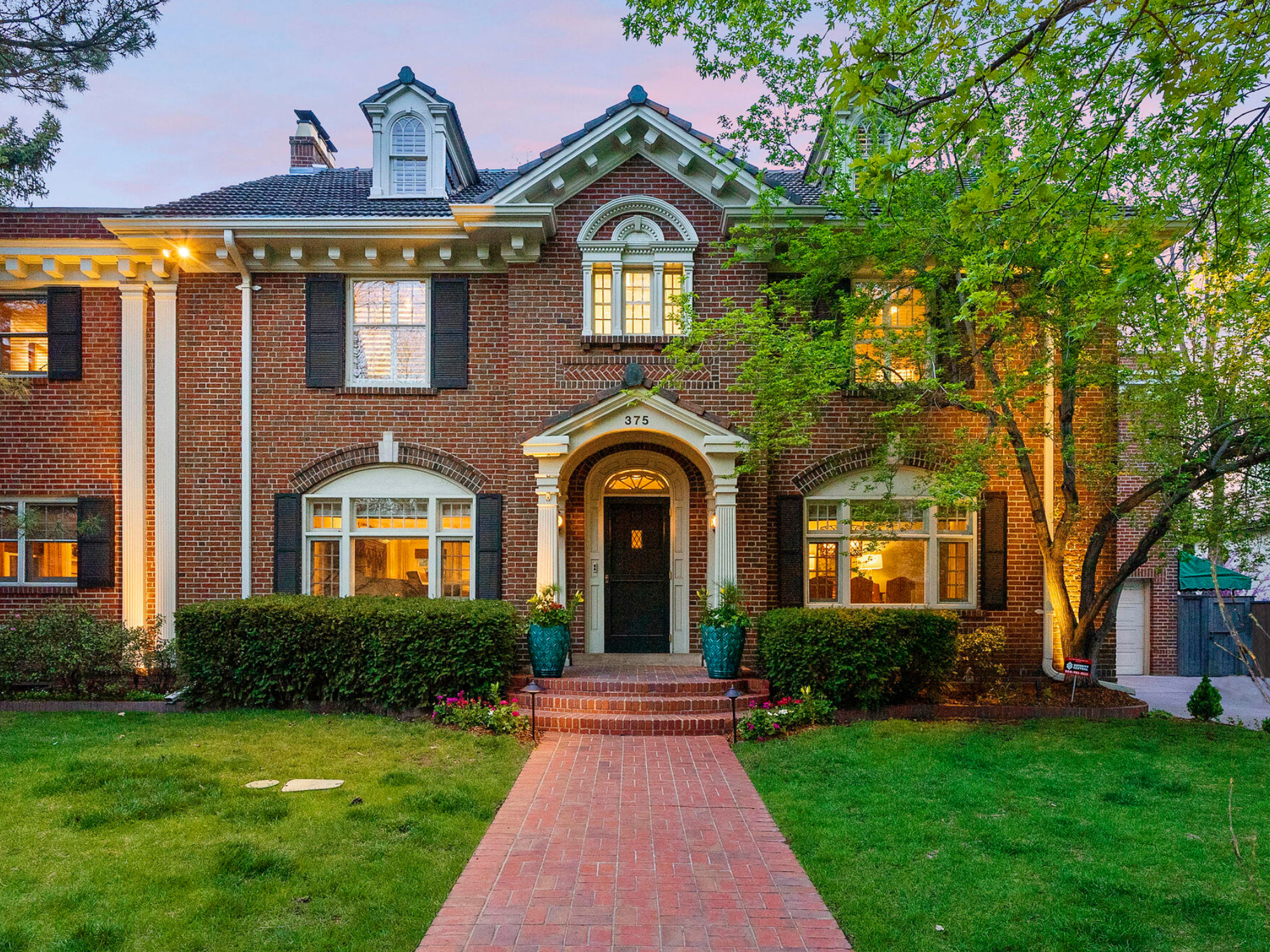 Twilight over a classic brick home with warm lighting and an inviting atmosphere.