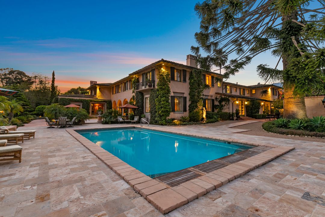 Large house by the blue pool under a sunset sky