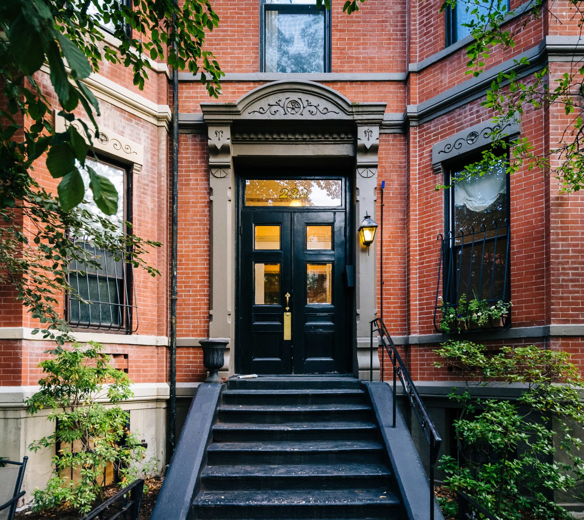 A red brick building with a black metal rail and a black door.