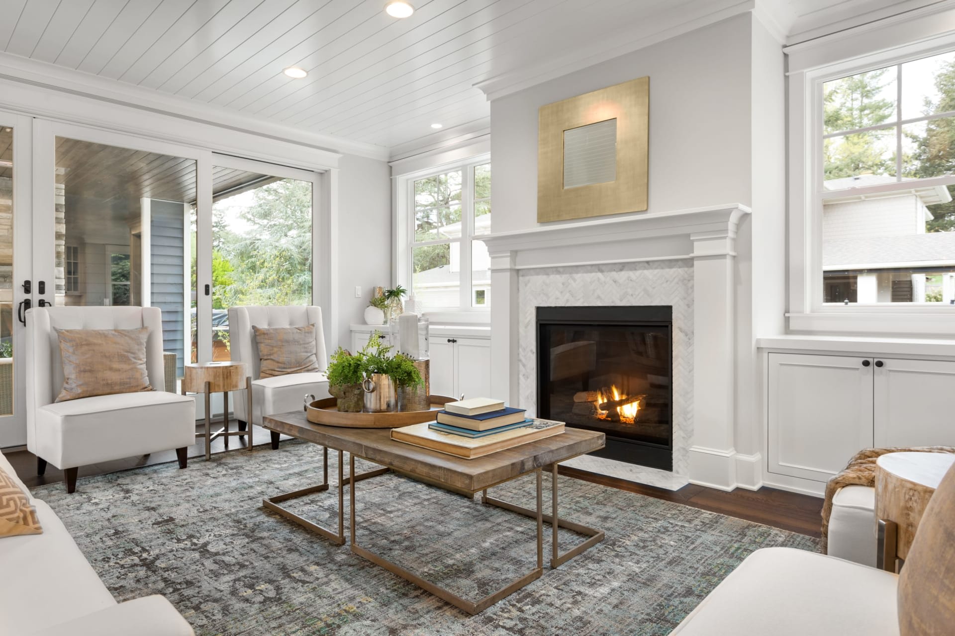 A modern living room painted in a light beige color with a fireplace, couches, chairs, coffee table, and sliding glass doors.