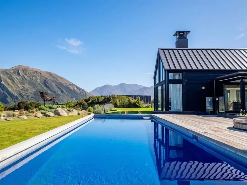 A modern black house with a swimming pool in the foreground