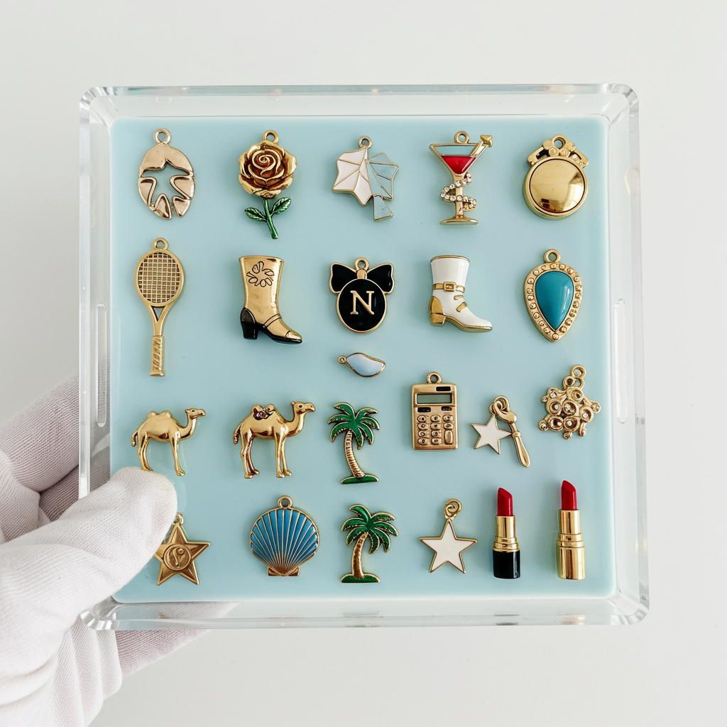 Acrylic tray of gold-tone personalized charms, including a rose, martini glass, tennis racket, and palm trees.